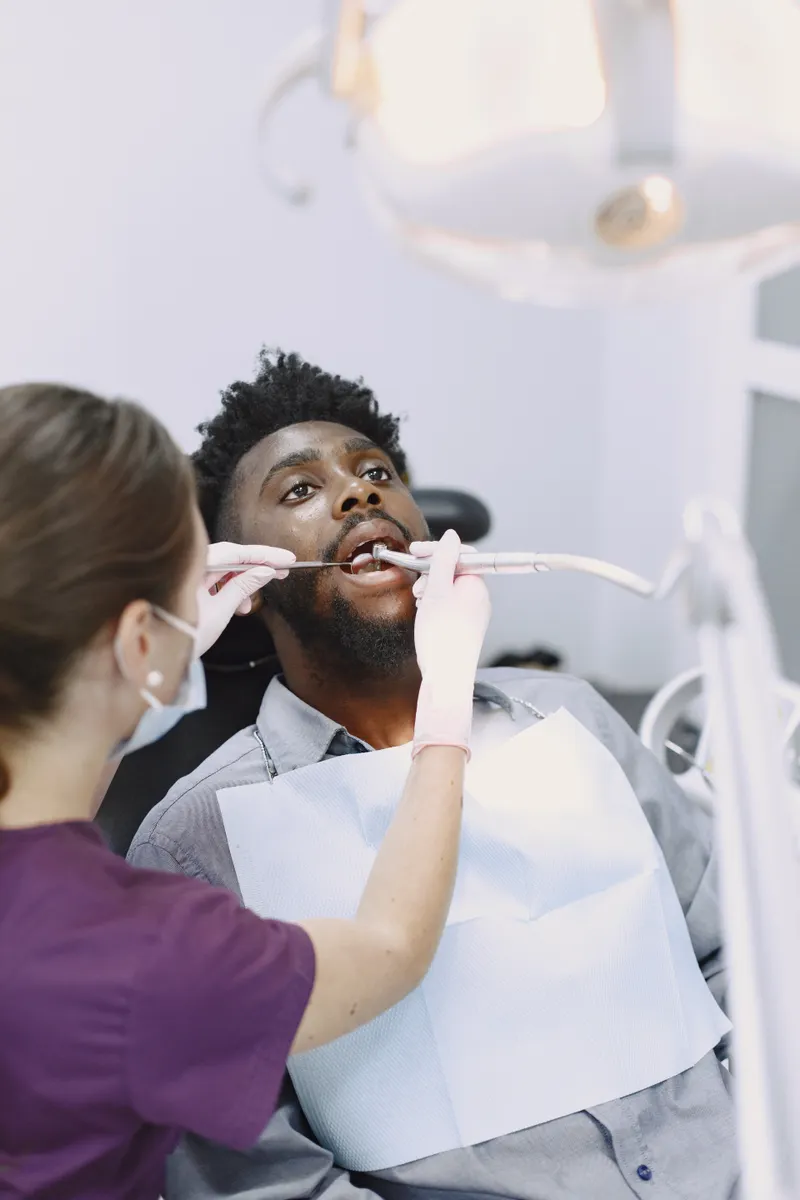A man in the dental chair has his teeth cleaned by a dental professional.